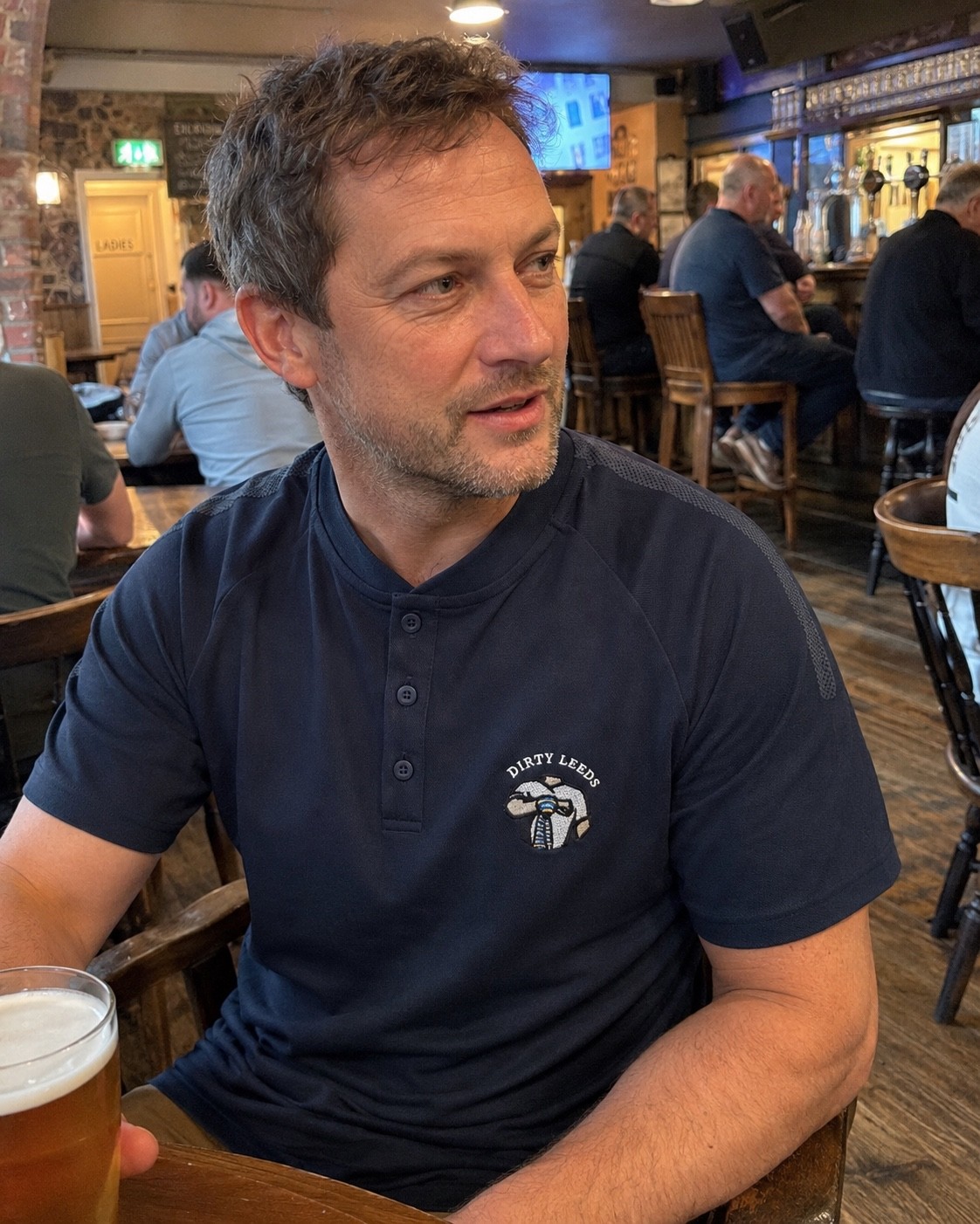 Dirty Leeds® Keep Fighting Salute Logo Navy Grandad Shirt – pub setting.