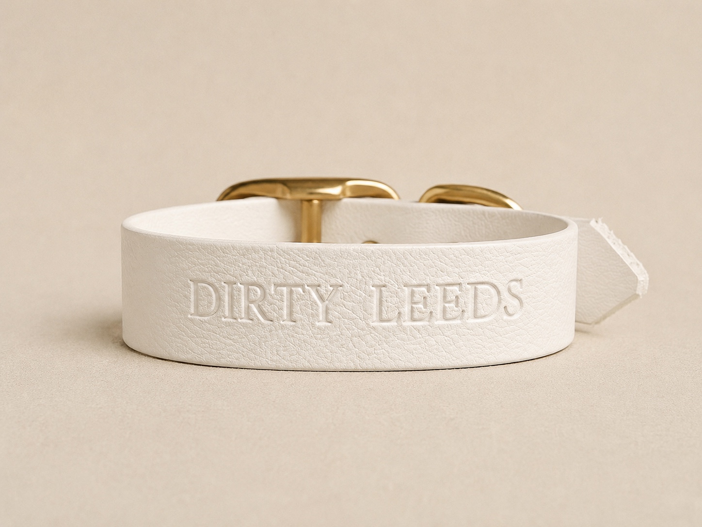 Reverse view of the Dirty Leeds® white dog collar showing the embossed DIRTY LEEDS lettering.