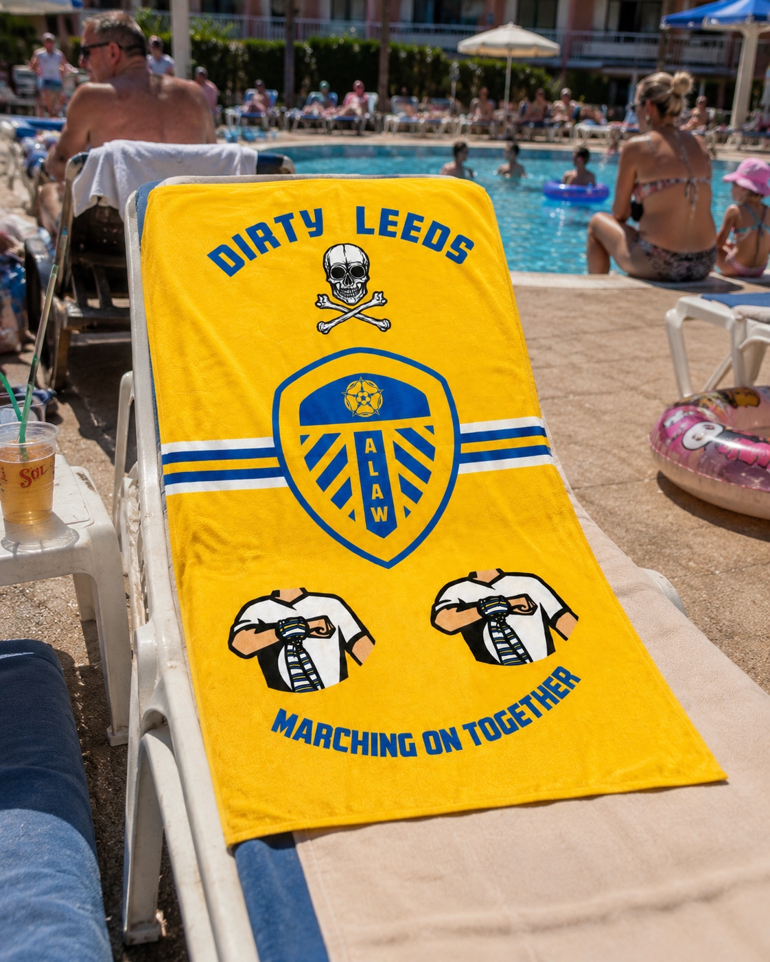 Yellow Dirty Leeds® beach towel laid out on a sunbed by the pool.